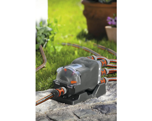 Distributeur d''eau automatique Gardena avec plusieurs tuyaux d''arrosage connectés à l''extérieur