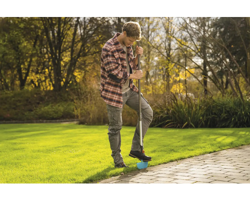 Ein Mann benutzt einen Rasenkantenstecher im Garten, um Rasenkanten zu bearbeiten