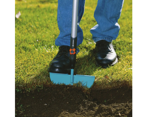 Person benutzt einen Rasenkantenstecher im Garten.