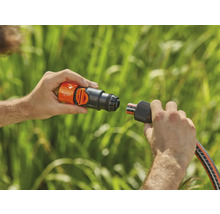 Une personne connecte un raccord de tuyau Gardena à un raccord de robinet.