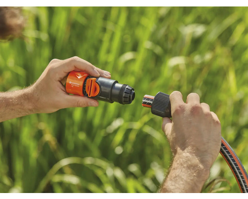 Une personne connecte un raccord de tuyau Gardena à un raccord de robinet.