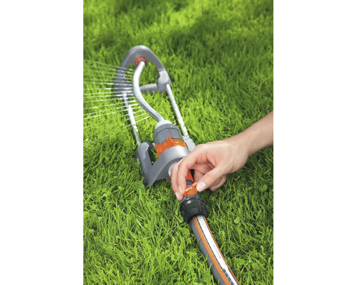 Arroseur de gazon en marche avec la main sur le régulateur sur la pelouse