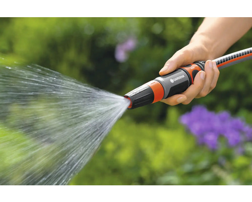 Une main tient un tuyau d''arrosage Gardena d''où jaillit de l''eau.
