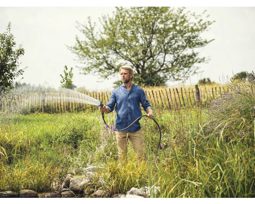 Homme arrosant le jardin avec un tuyau d''arrosage et un pistolet d''arrosage