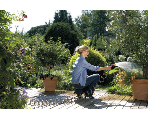 Femme arrosant des plantes avec un tuyau d''arrosage dans un jardin