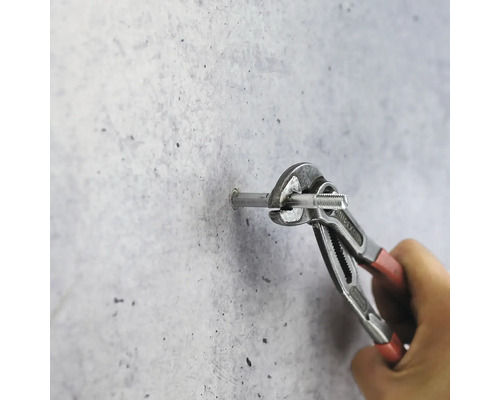 Une personne fixe une vis dans un mur avec une pince multiprise.