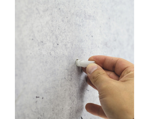 La main insère une cheville dans le mur