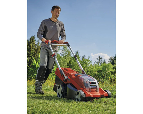 Un homme pousse une tondeuse à gazon rouge à batterie dans le jardin