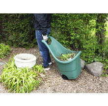 Une personne tire un chariot de jardin rempli de déchets de jardin dans un jardin