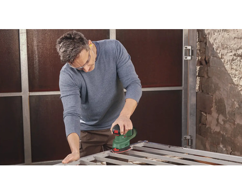 Homme ponçant un cadre métallique avec une ponceuse