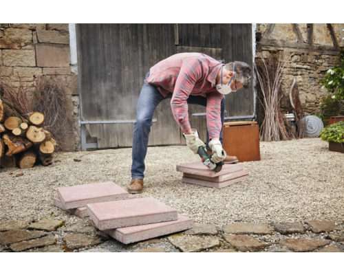 Artisan coupant des pavés avec une meuleuse d'angle à l'extérieur.