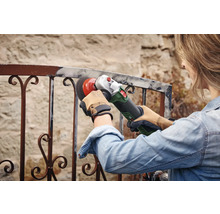 Femme ponçant une balustrade en métal avec une meuleuse d'angle
