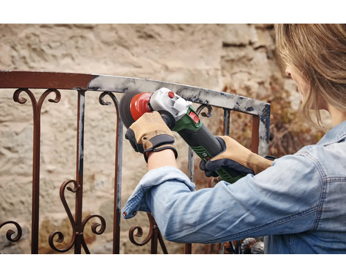 Femme ponçant une balustrade en métal avec une meuleuse d'angle