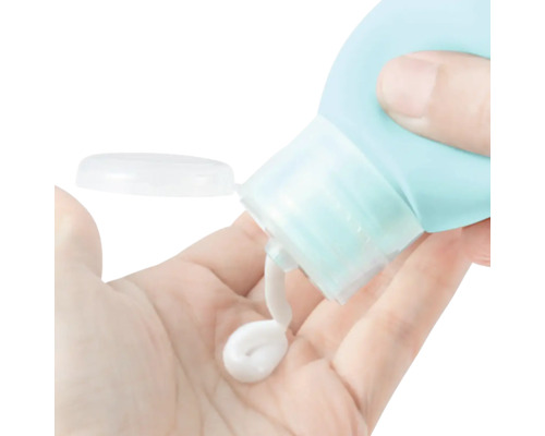 Une main tient un flacon de voyage et dose une petite quantité de lotion
