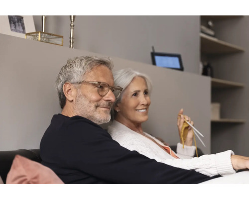 Älteres Paar sitzt auf der Couch und strickt