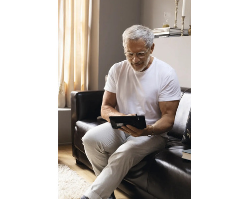 Mann sitzt auf einem Sofa und nutzt ein Tablet