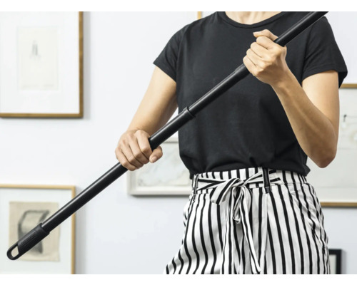 Une personne tient un manche de serpillère noir.