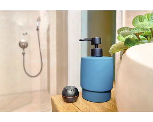 Badezimmerszene mit Seifenspender und Aromatherapie-Diffusor auf einem Holztisch