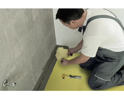 Un artisan pose du ruban d''étanchéité dans une salle de bain