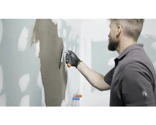 Homme enduisant un mur avec du mastic