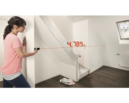 Frau misst Raum mit Laser-Entfernungsmesser