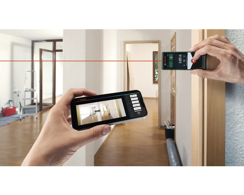 Une personne mesure une pièce avec un télémètre laser et un smartphone. Logo Bosch.