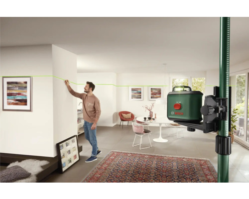 Scène d''intérieur avec un homme marquant une ligne laser verte sur un mur à l''aide d''un laser lignes croisées