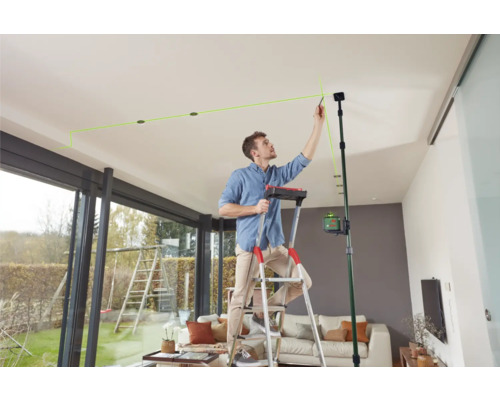 Homme sur une échelle faisant des marques au plafond avec un laser linéaire.