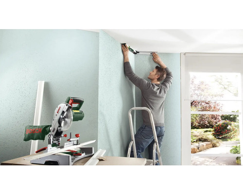 "Un homme installe une moulure de plafond avec un niveau 