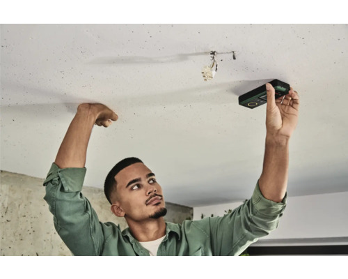 Ein Mann verwendet ein digitales Messgerät an einer Decke.