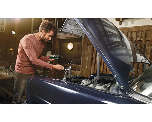 Un homme vérifie la batterie de voiture avec un testeur de batterie dans un garage