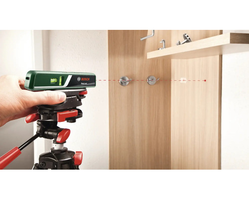 Logo Bosch. Niveau laser sur trépied alignant une ligne laser rouge sur une armoire