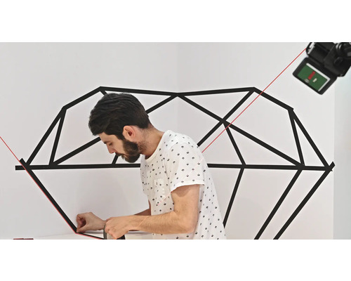 Mann klebt geometrisches Muster mit Klebeband an die Wand