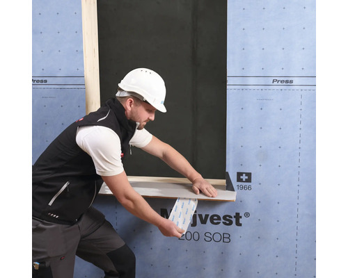 Un artisan fixe une bande d''étanchéité sur un cadre de fenêtre sur un chantier