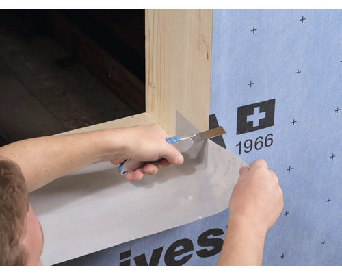 Application d''un film de construction avec un couteau sur un cadre de fenêtre