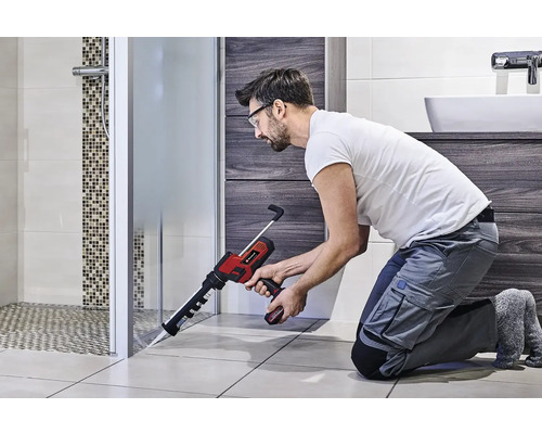 Handwerker benutzt eine Akku-Kartuschenpistole im Badezimmer zur Abdichtung einer Duschkabine.