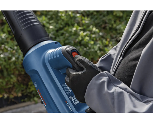 Une personne utilise un souffleur de feuilles dans le jardin.