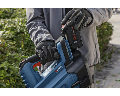 Une personne insère une batterie dans un corps de taille-haie.