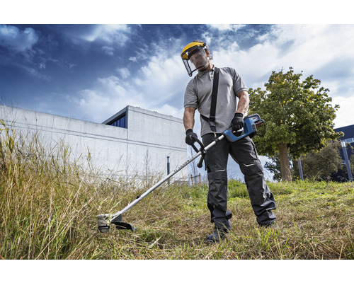 Une personne utilise un coupe-bordure avec une visière de protection dans le jardin.