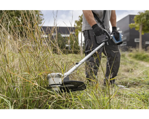 Un homme coupe l'herbe avec un coupe-bordure.