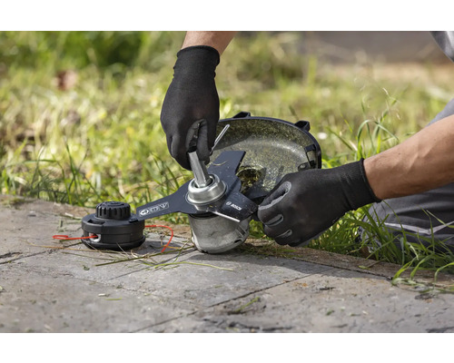 Un homme change la lame d'un coupe-bordure.