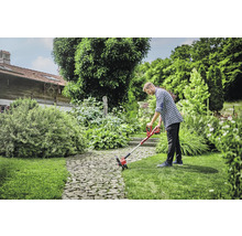 Un homme utilise un coupe-bordure à batterie dans le jardin.