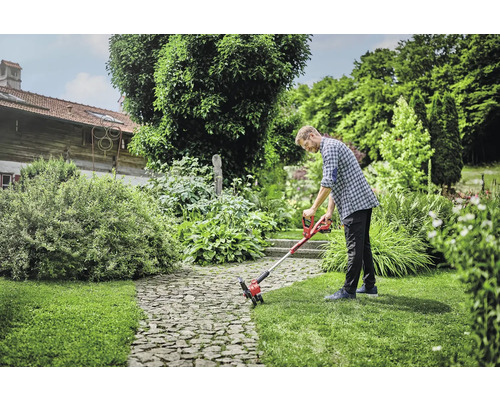 Un homme utilise un coupe-bordure à batterie dans le jardin.