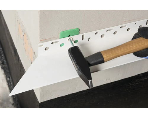 Anbringen eines Abschlussprofils mit einem Hammer an einer Fassade