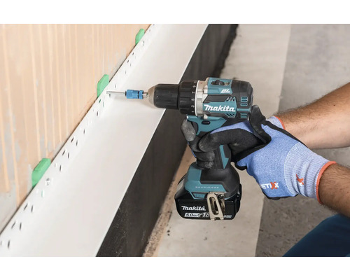 Handwerker befestigt Sockelschiene mit Akku-Bohrschrauber von Makita