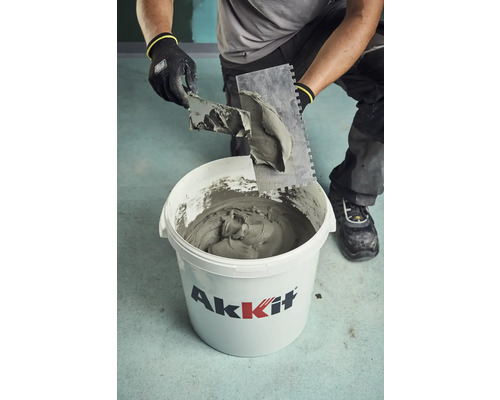 Un artisan sort de la colle à carrelage d''un seau Akkit avec une truelle