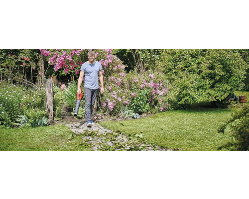 Mann benutzt einen Laubsauger im Garten.