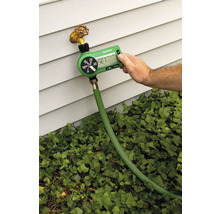 Gartenbewässerungscomputer an einem Wasserhahn mit Schlauch angeschlossen, die Bewässerung wird von einer Person eingestellt.