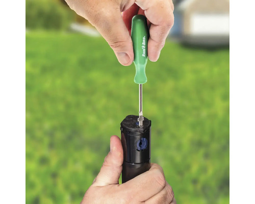 Une personne ajuste un arroseur à l''aide d''un tournevis Rain Bird.