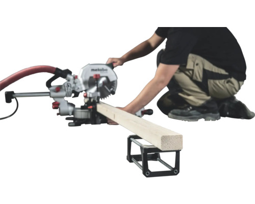 Une personne utilise une scie à onglet Metabo pour couper un morceau de bois posé sur un support.